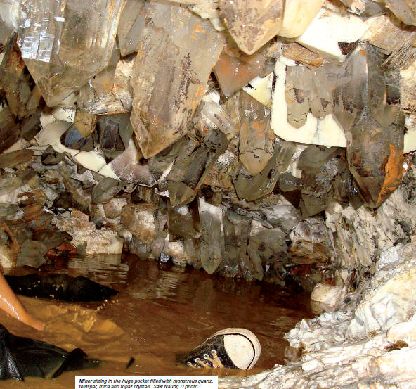 Miner sitting in the huge pocket filled with monstrous quartz, feldspar, mica and topaz crystals. Saw Naung U photo.