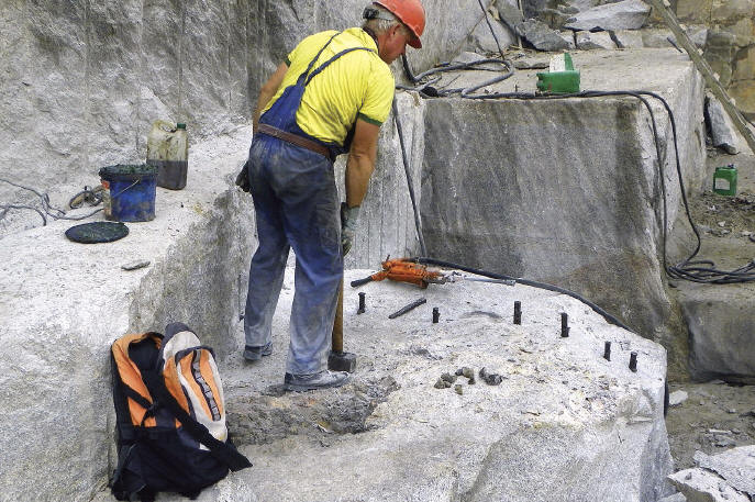 Quarry worker preparing to split one of the granite blocks in which pockets were found (pocket visible between backpack and miner’s boot). A. Korzekwa photo.